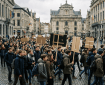 Crowd of students marching with blank placards through a historic city square
